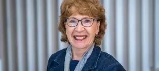 Professor Hilary Critchley is wearing a blue denim jacket and smiling at the camera