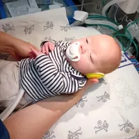 Baby wearing ear protectors be laid in a cot