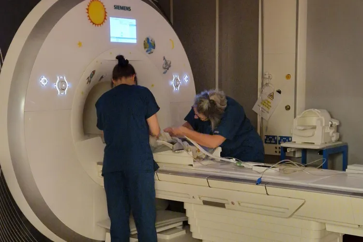 Two clinicians supporting baby in MRI machine