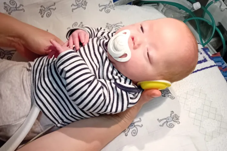 Baby wearing ear protectors be laid in a cot