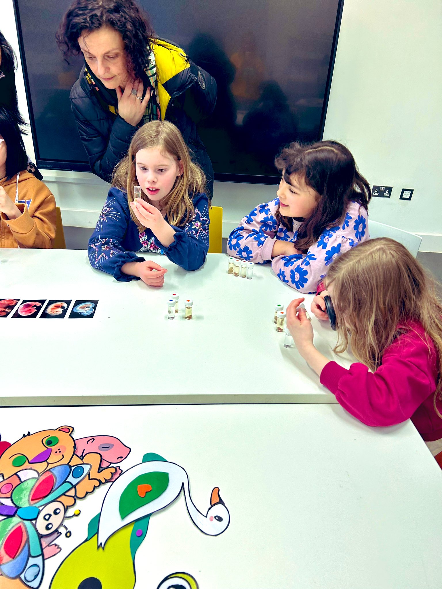 A group of 9-12 year old girls examine vials with biological matter inside.